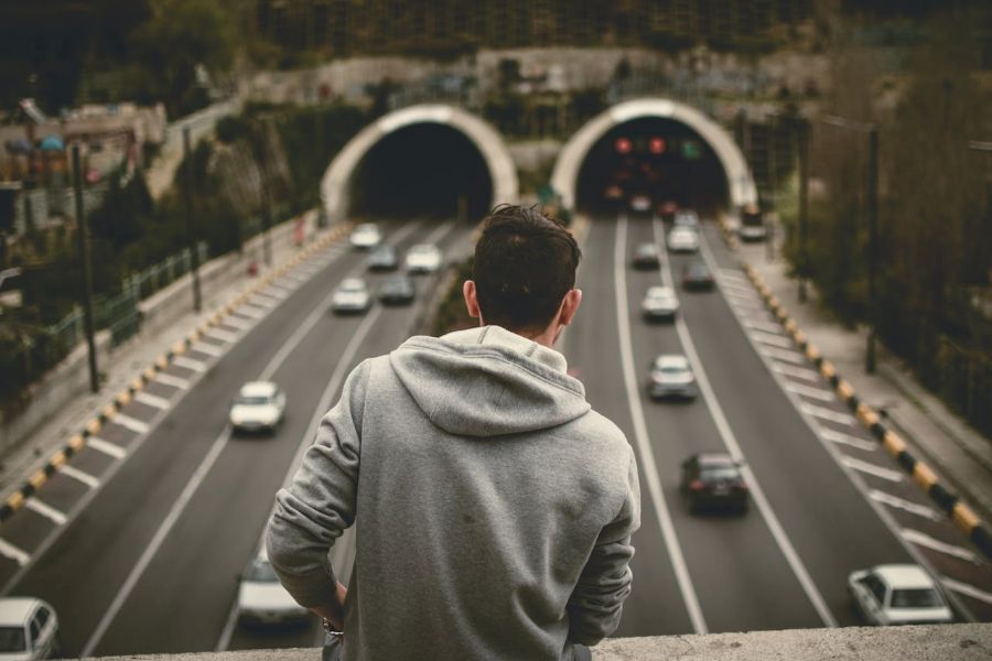 Homem observando duas entradas de túnel em uma rodovia movimentada, simbolizando o momento de decisão estratégica sobre qual caminho seguir ao escolher um CRM empresarial.