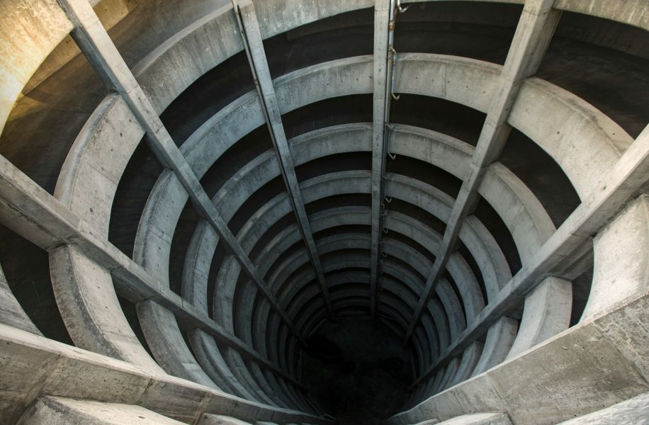Vista superior de uma estrutura circular em espiral, lembrando um funil profundo de concreto, simbolizando as etapas do funil de vendas e a profundidade da jornada do cliente com o apoio da inteligência artificial.