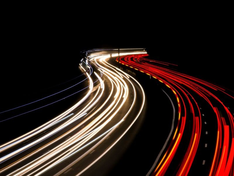 Traços de luz em uma estrada escura simbolizando fluxo contínuo, velocidade e direção — representando a agilidade e o movimento de dados em um sistema de CRM.