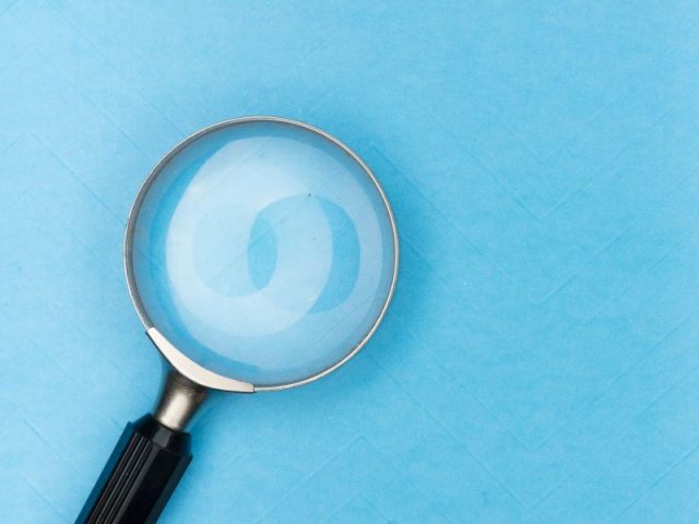 Lupa sobre fundo azul simbolizando análise, busca de informações e identificação de oportunidades no processo de vendas.