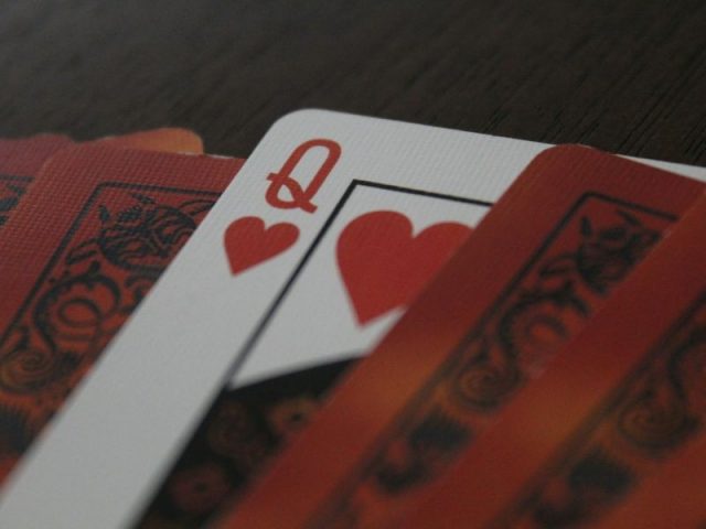 Cartas de baralho sobre mesa, com destaque para a dama de copas, simbolizando estratégia, tomada de decisão e leitura de cenário nas vendas consultivas.