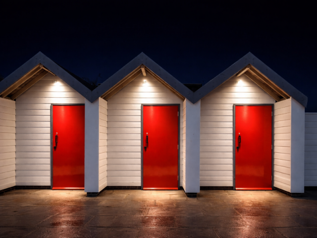 Na imagem, três portas vermelhas de um conjunto de casas brancas que fazem alusão aos 03 erros a serem evitados mencionados neste artigo que fala de IA e CRM.